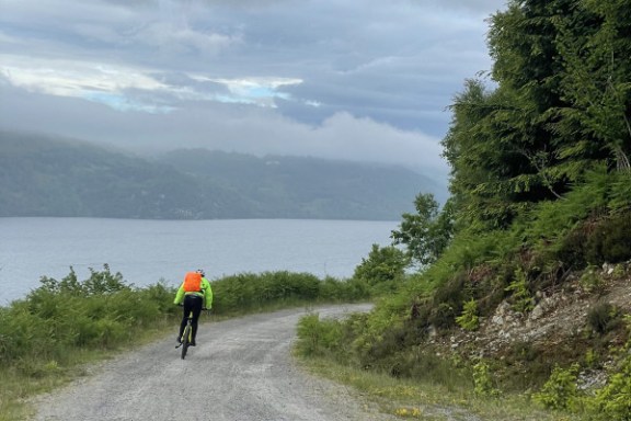 a man walking down a dirt road next to a body of water