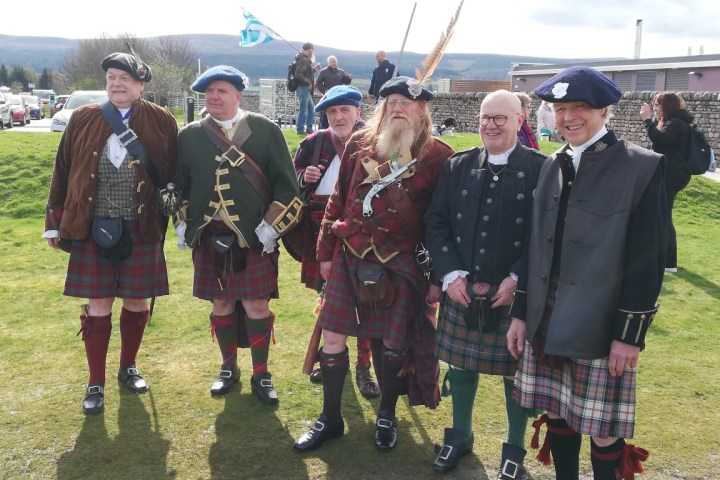 a group of people standing in a field posing for the camera