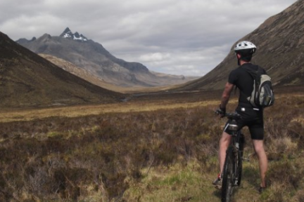 a man riding a bicycle with a mountain in the background