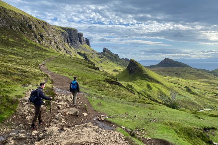 a group of people on a rocky hill with Quiraing in the background