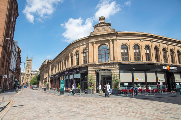 Outdoor dining area next to a historic building on a sunny day with a tower in the background.