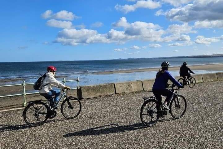a group of people riding bikes on a beach