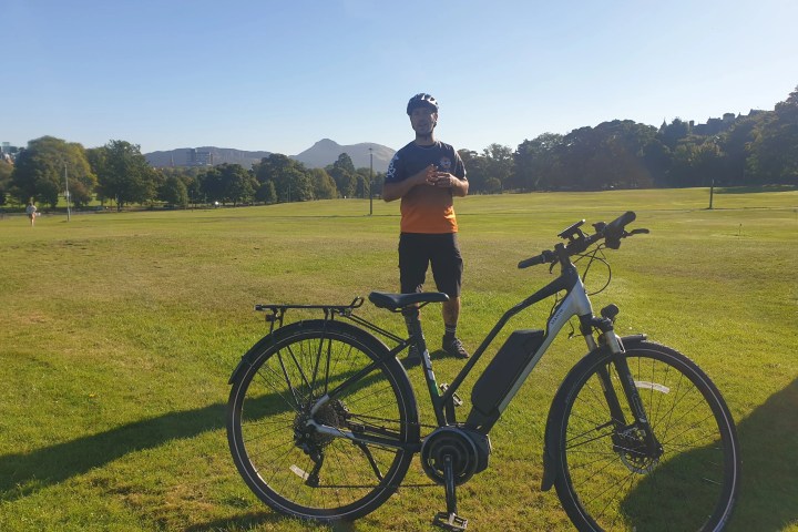 a man standing on a lush green field next to a bicycle