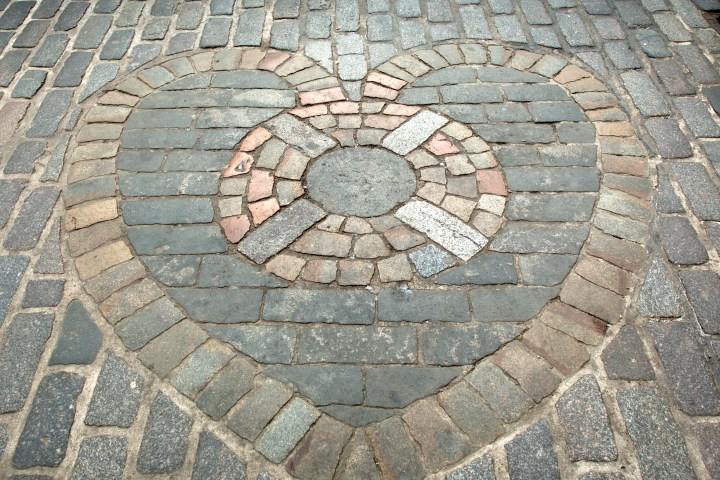 Heart shape made of stones on a cobblestone street.