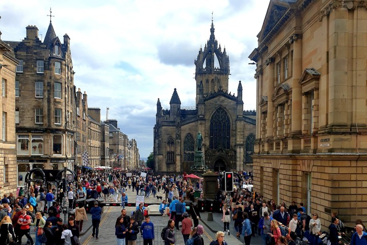 Crowded street with ornate buildings and a church in the background.
