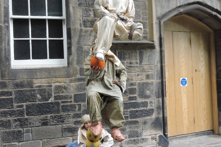 Street performers creating an illusion of floating, stacked on each other.